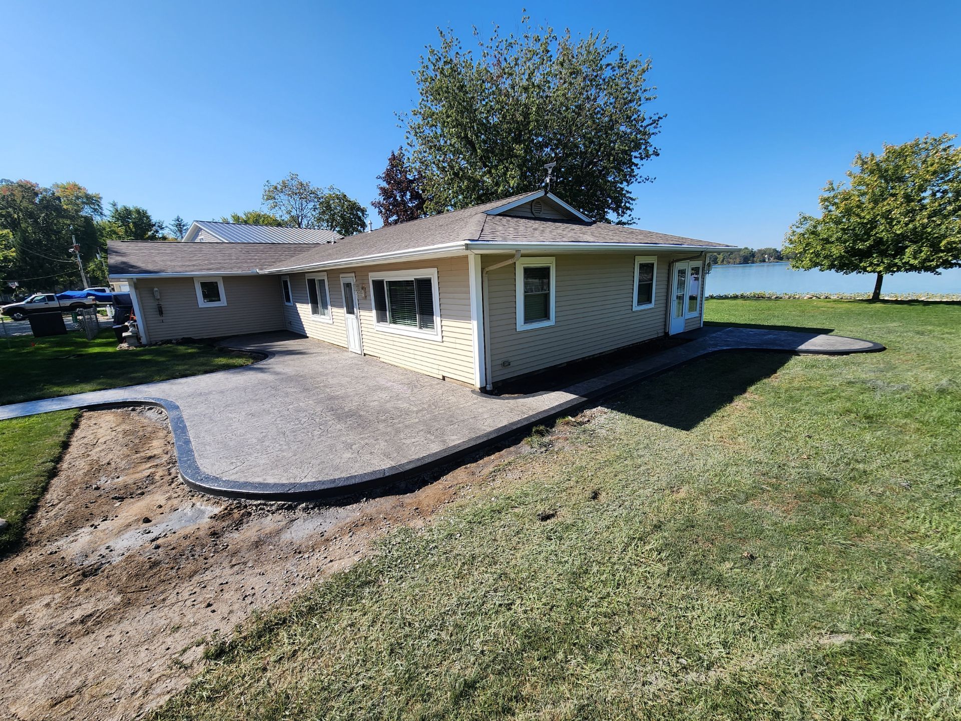 A house with a patio in front of it and a lake in the background.