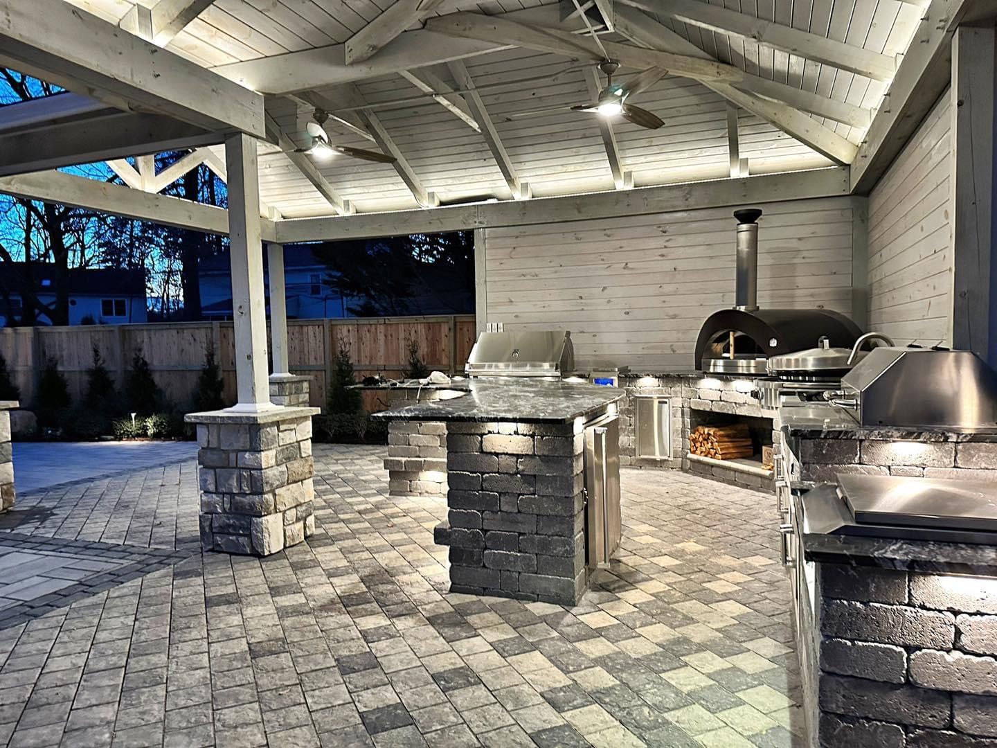 A woman is standing in front of a brick house with a bunch of furniture in the backyard.