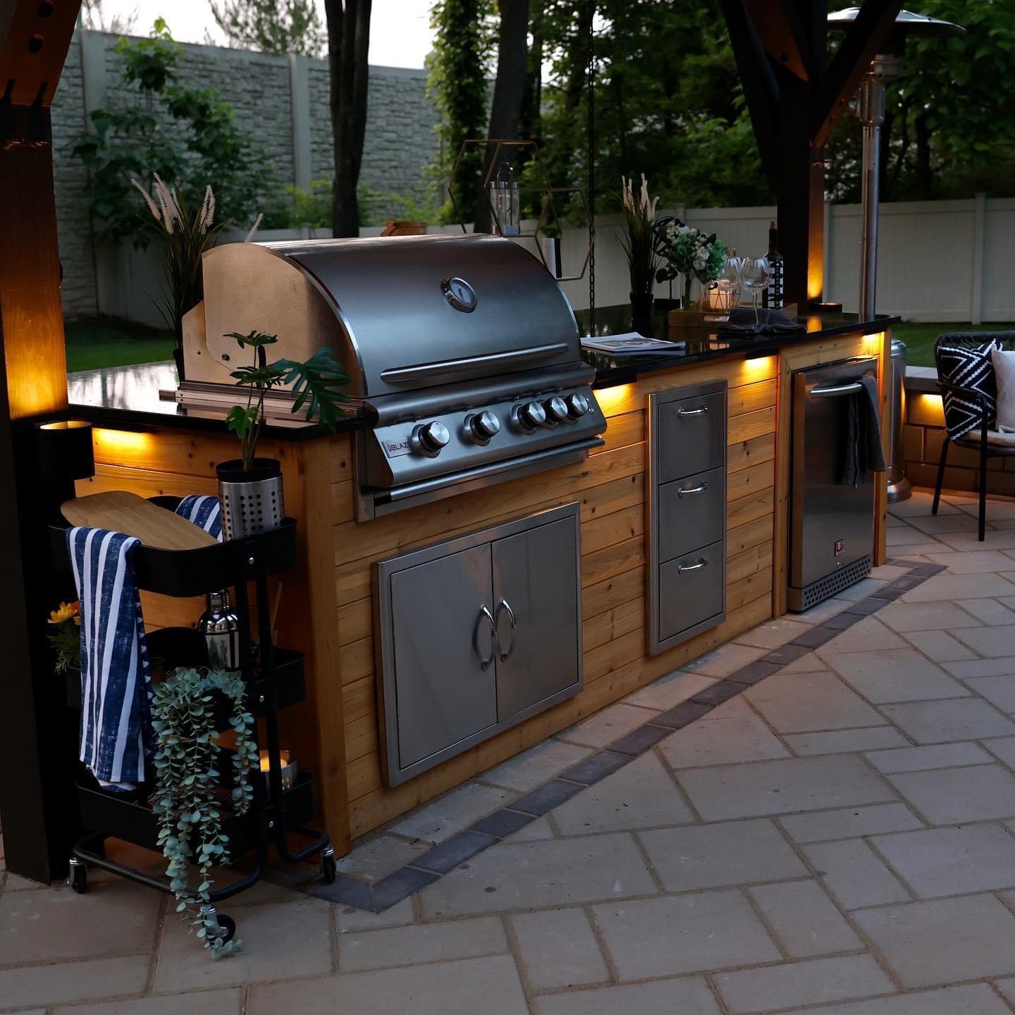 An outdoor kitchen with a stainless steel grill and cabinets