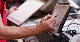 Un uomo scrive su un blocco appunti mentre utilizza un computer portatile.