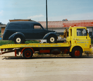 Un carro attrezzi giallo trasporta un'auto nera