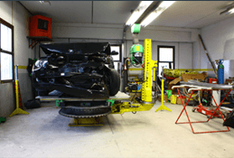 Un'auto è parcheggiata su un ponte sollevatore giallo in un garage.