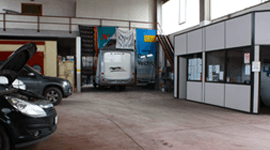 Una fila di auto è parcheggiata in un garage con il cofano alzato.