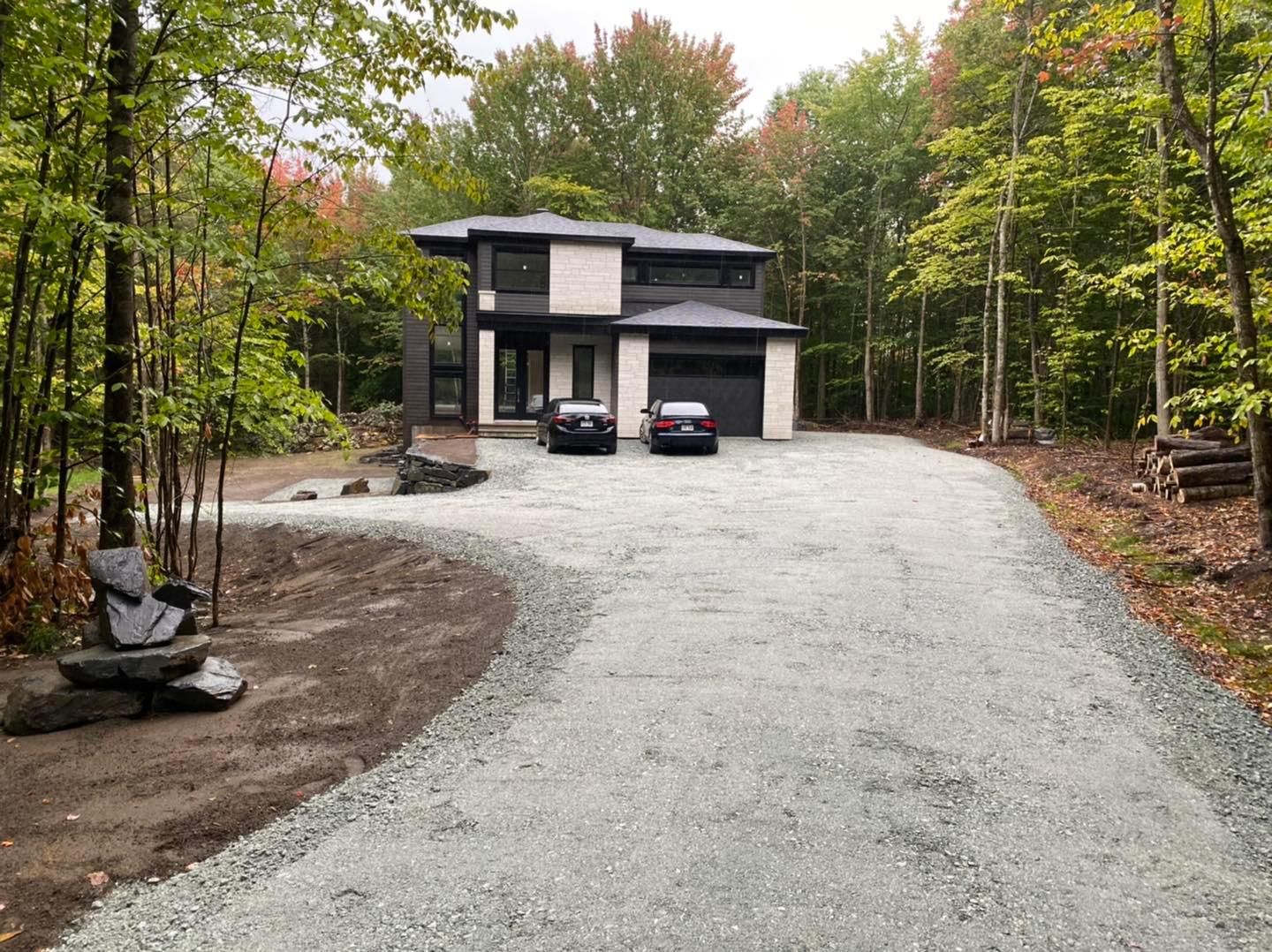 Deux voitures sont garées devant une maison dans les bois.
