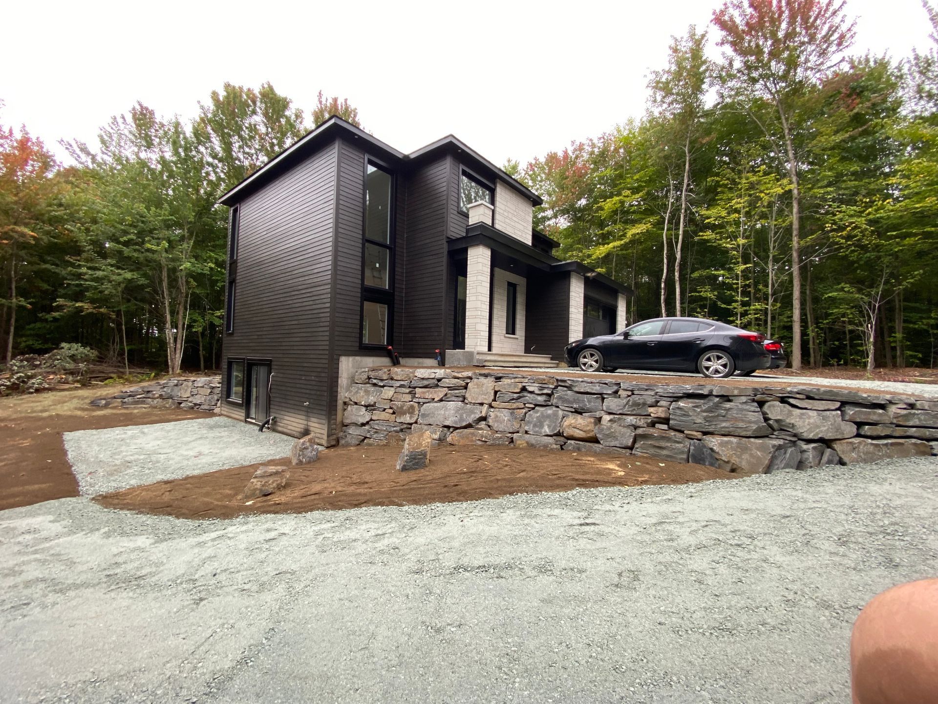 Une voiture noire est garée devant une maison noire et blanche.