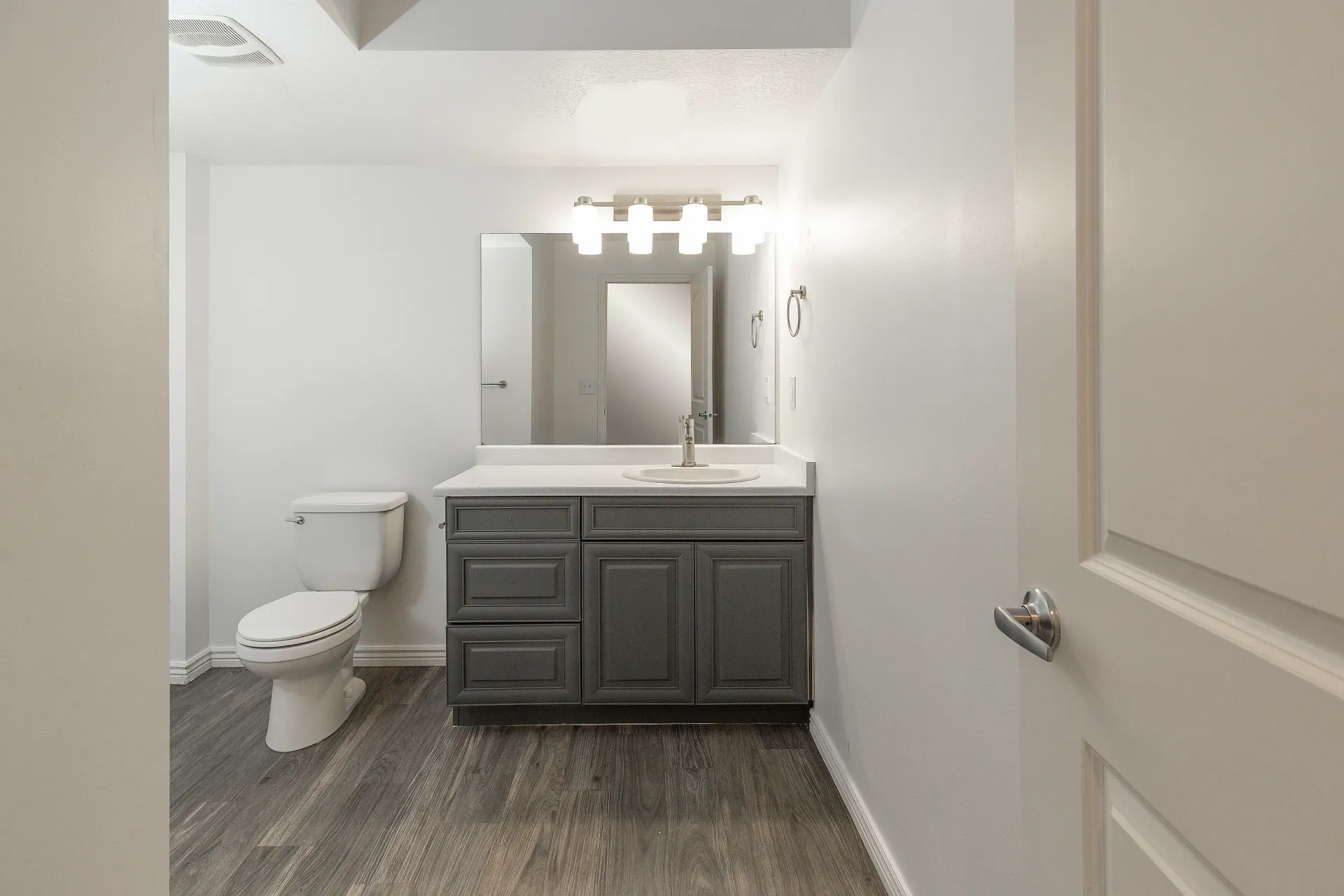 Bathroom with a toilet, vanity with sink, and mirror.