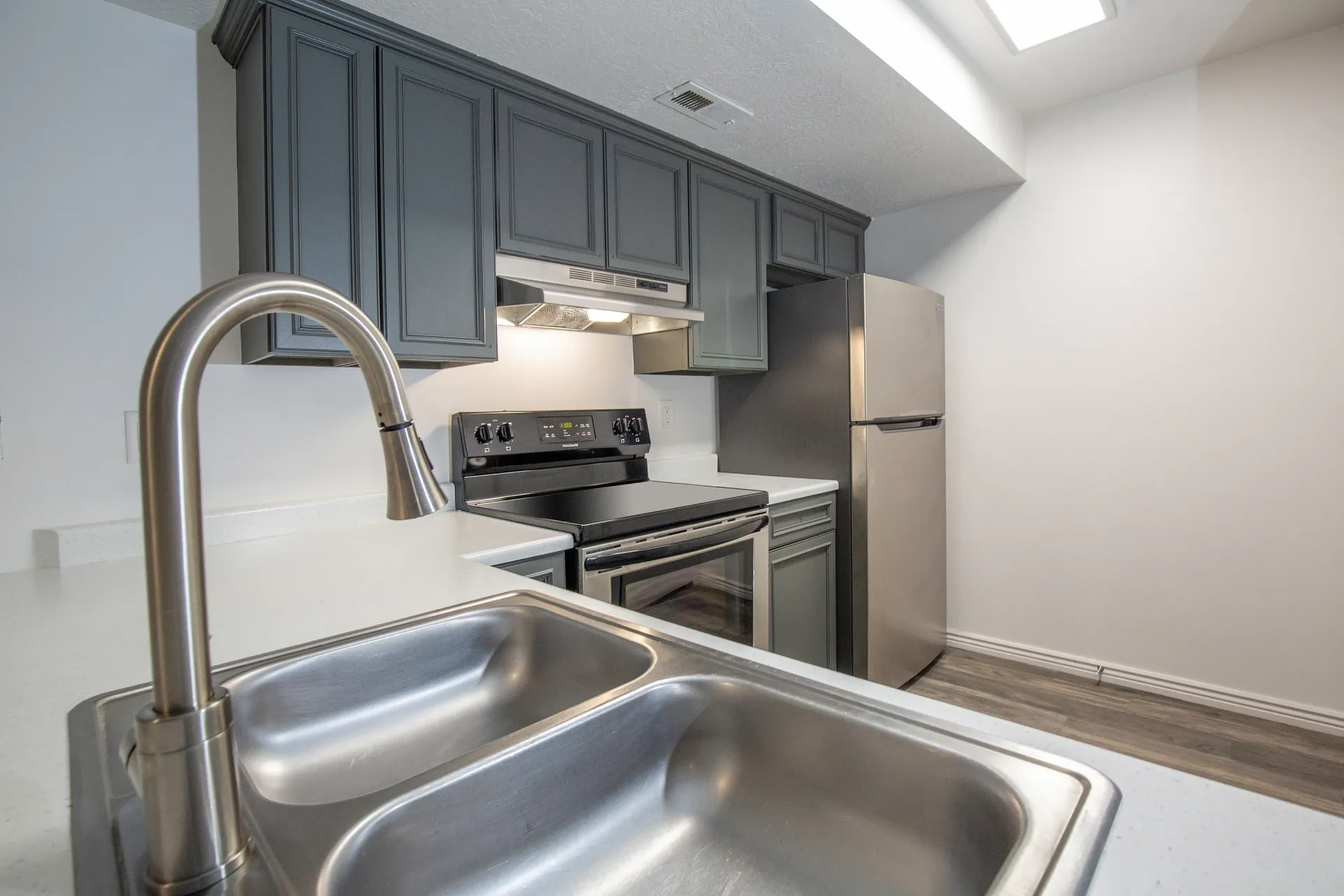 Modern kitchen with stainless steel appliances, gray cabinets, and a double basin sink.