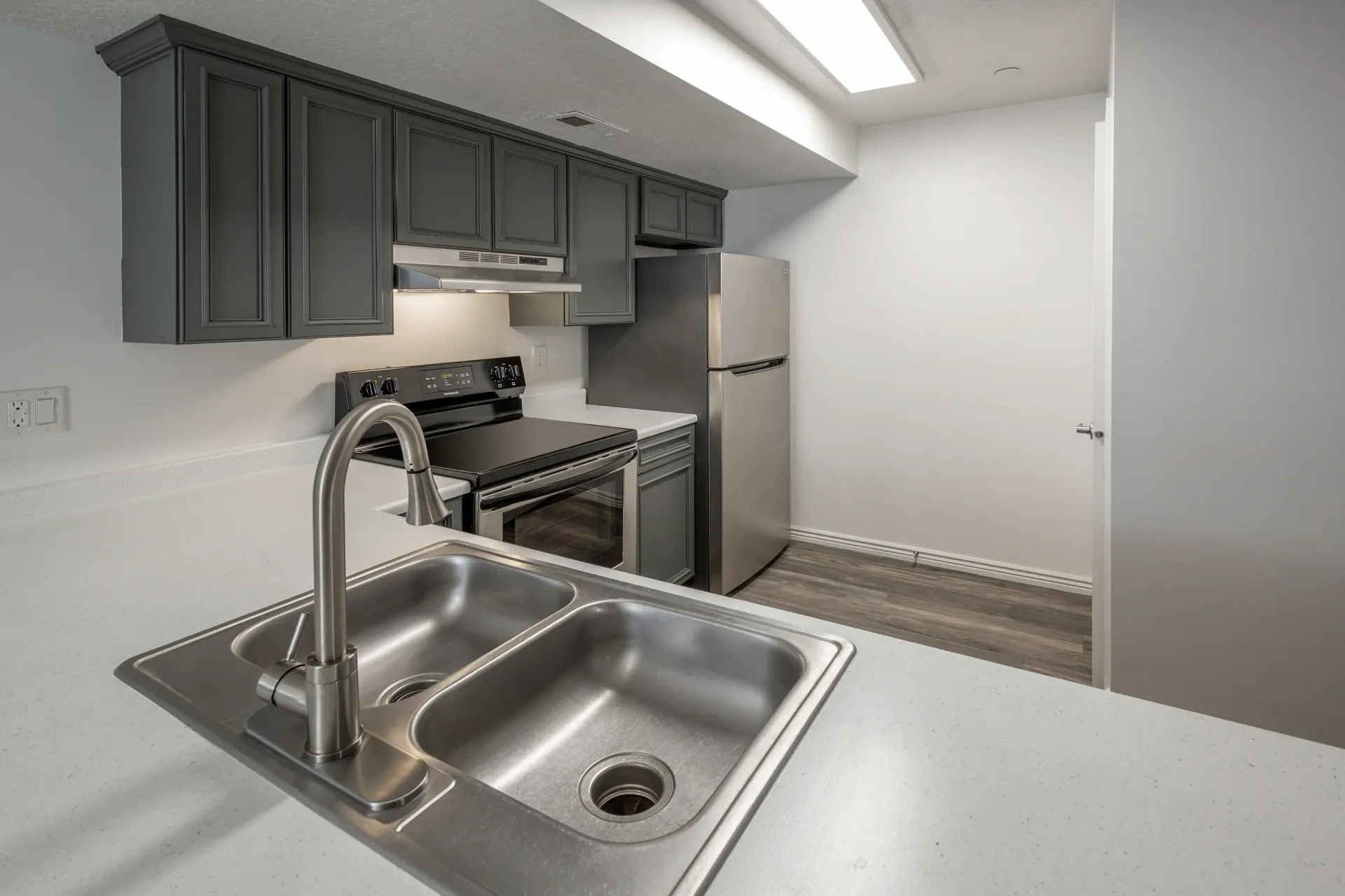 Modern kitchen with dark gray cabinets, stainless steel appliances, and a double basin sink.