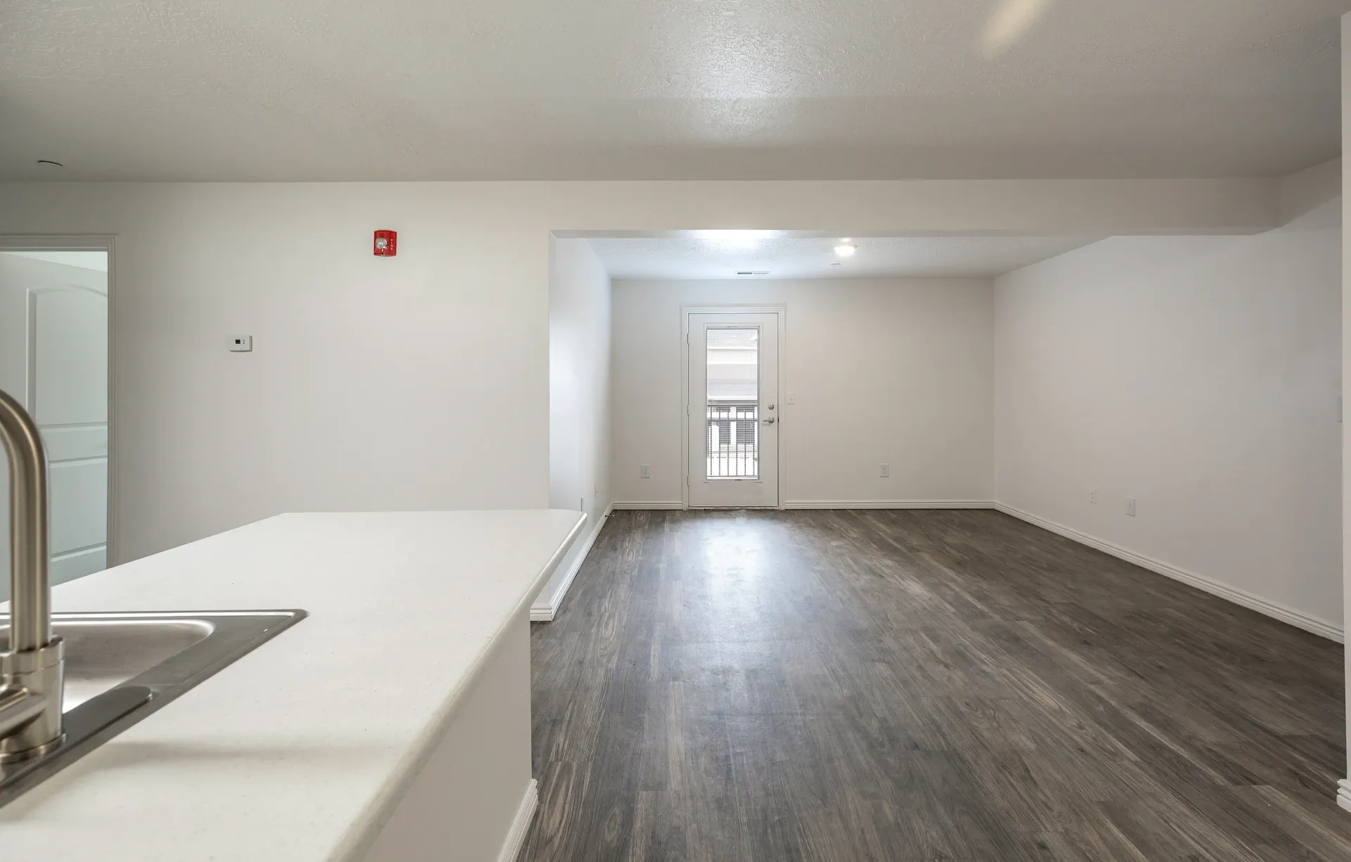 Interior view of an empty apartment with a kitchen island and a living area.