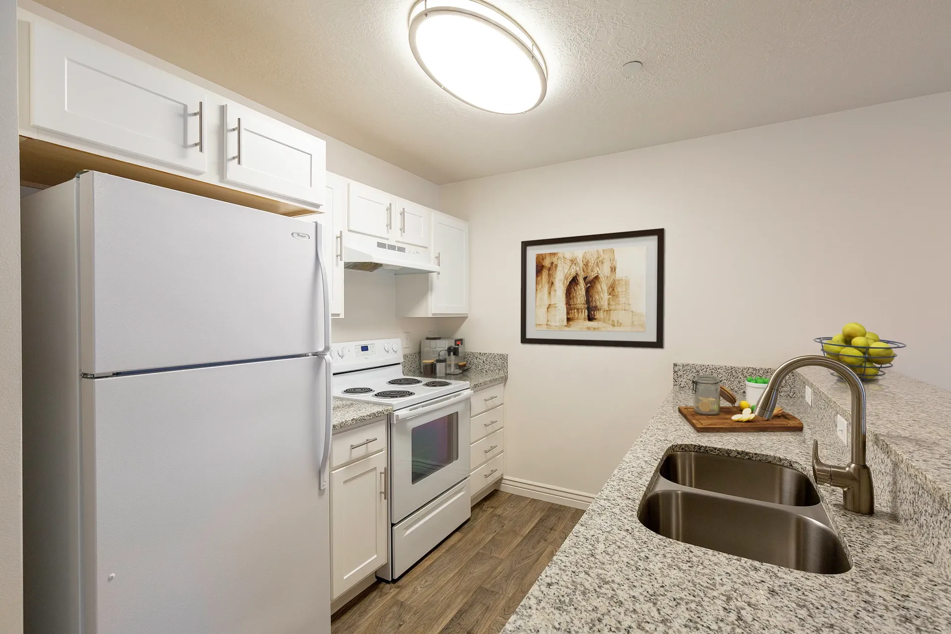 Modern kitchen with white appliances, granite countertops, and a double sink.