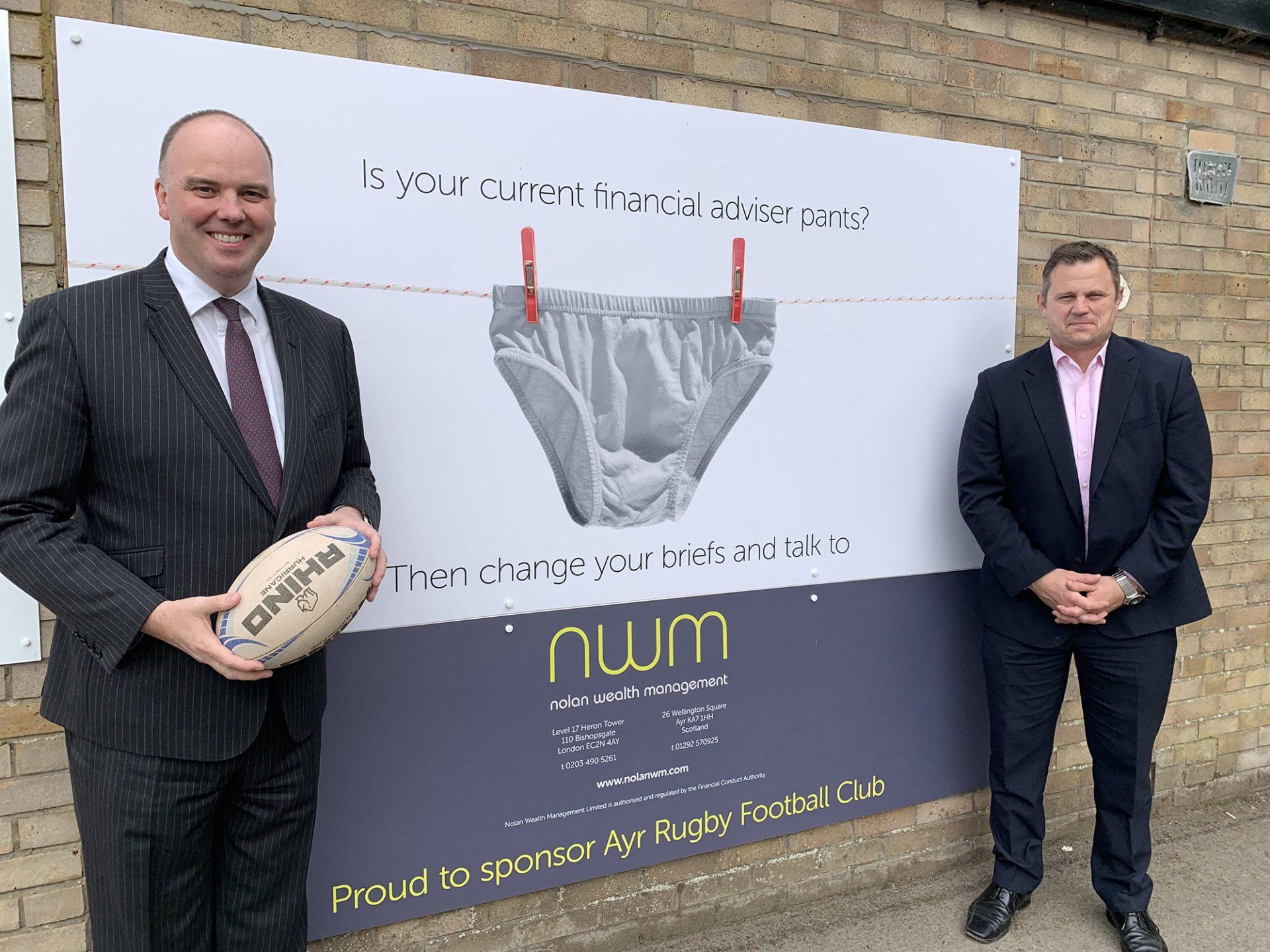 Gary pictures with Ayr Rugby C.O.O Glen Tippet next to NWM's sponsor's board