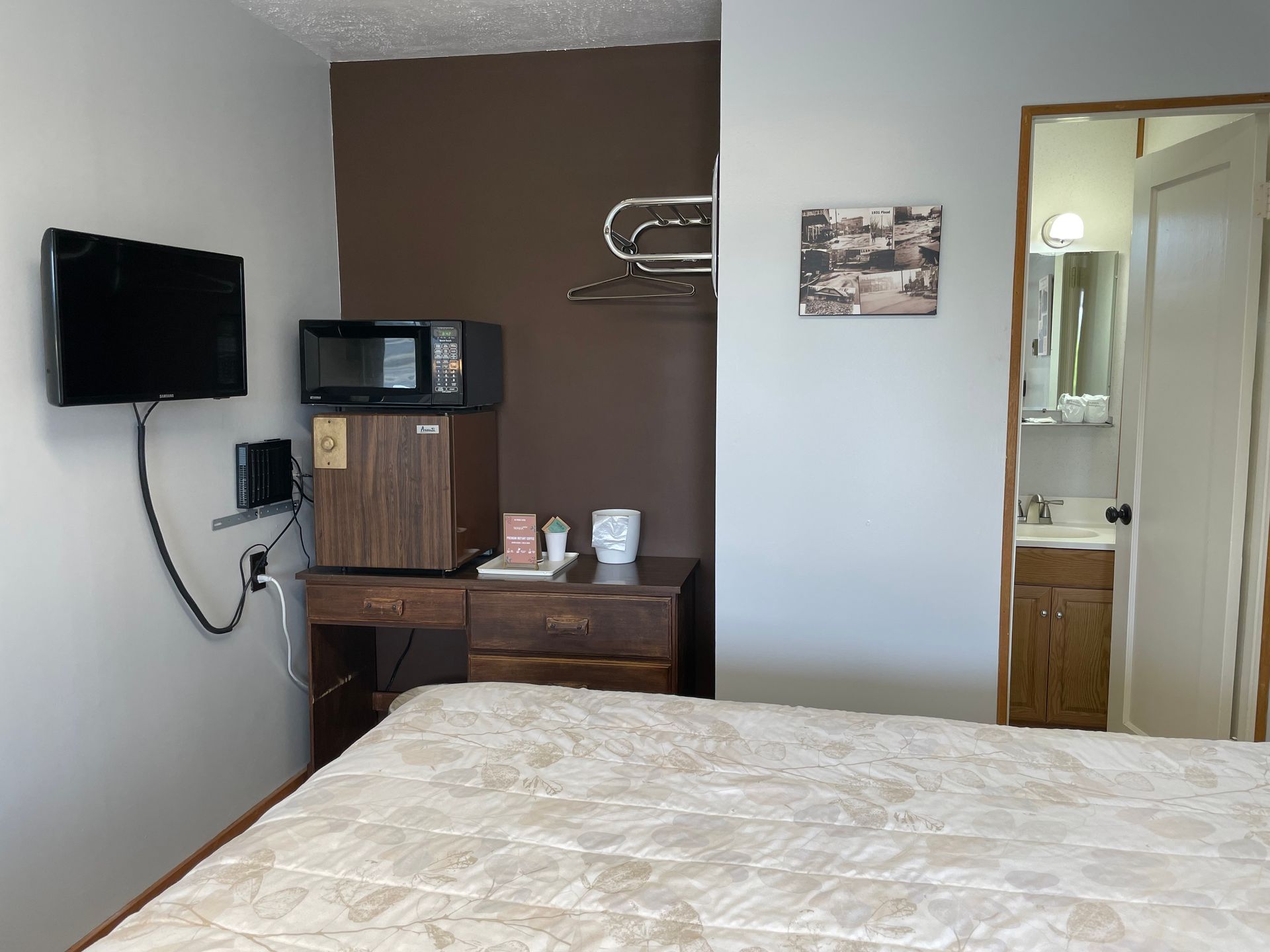 A hotel room with a bed , television , refrigerator and microwave