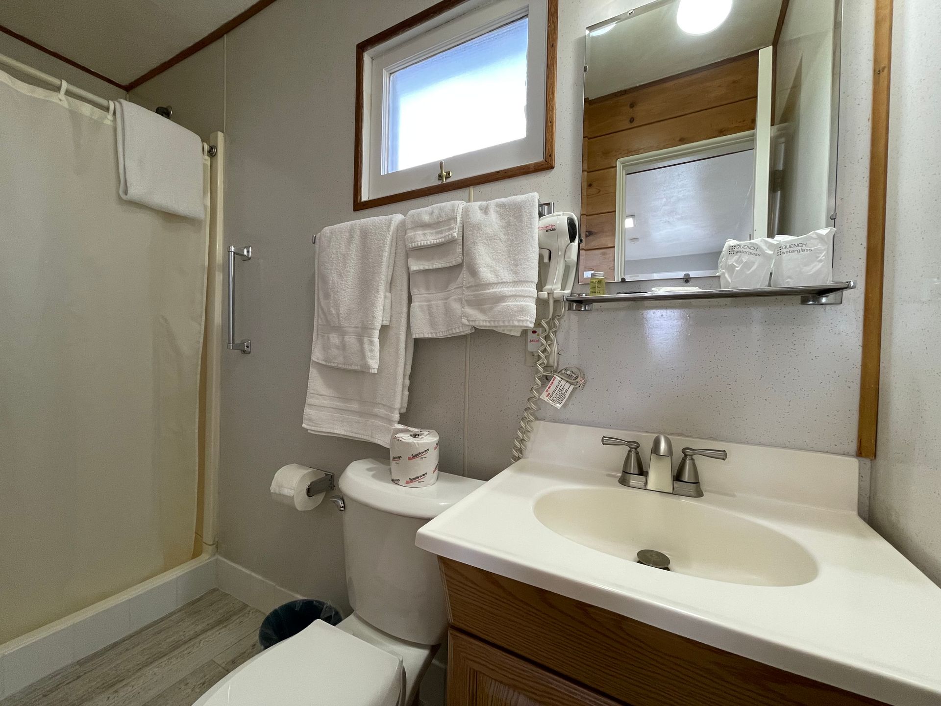 A bathroom with a toilet , sink , mirror and shower.