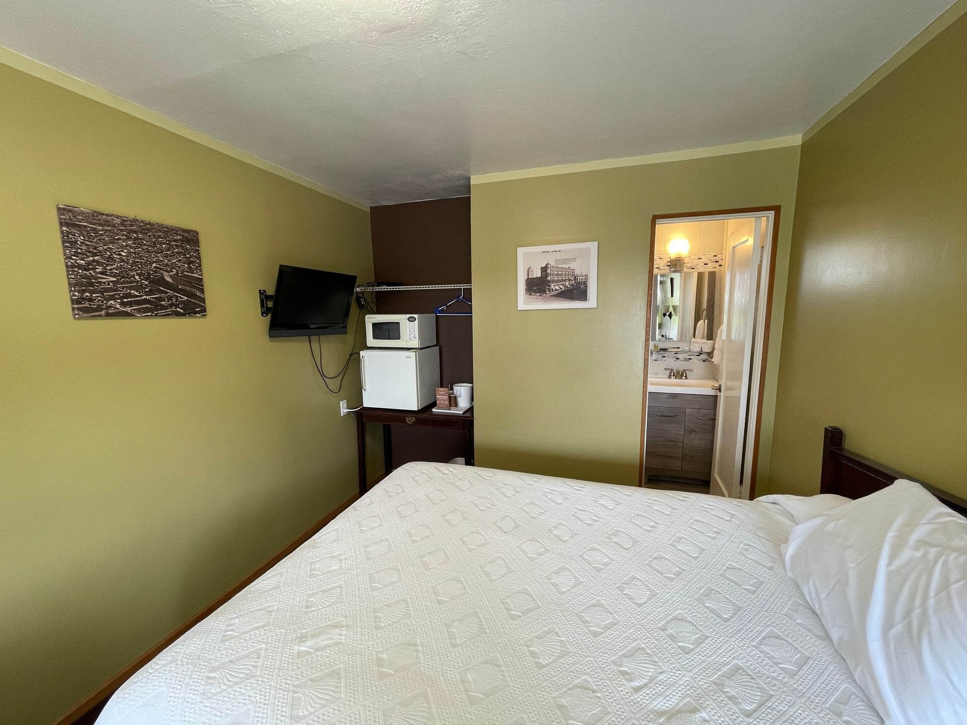 A hotel room with a king size bed and a microwave.