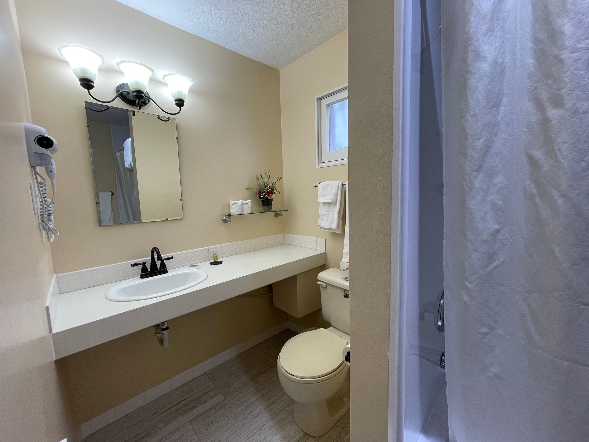 A bathroom with a toilet , sink , mirror and shower.
