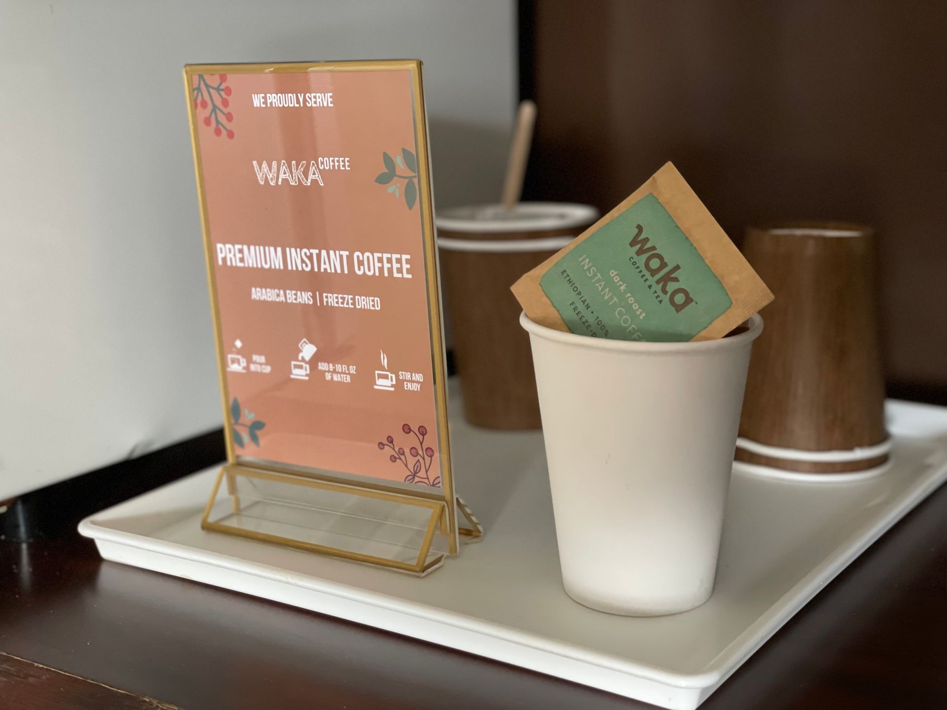 A cup of coffee is sitting on a tray next to a sign that says premium instant coffee.