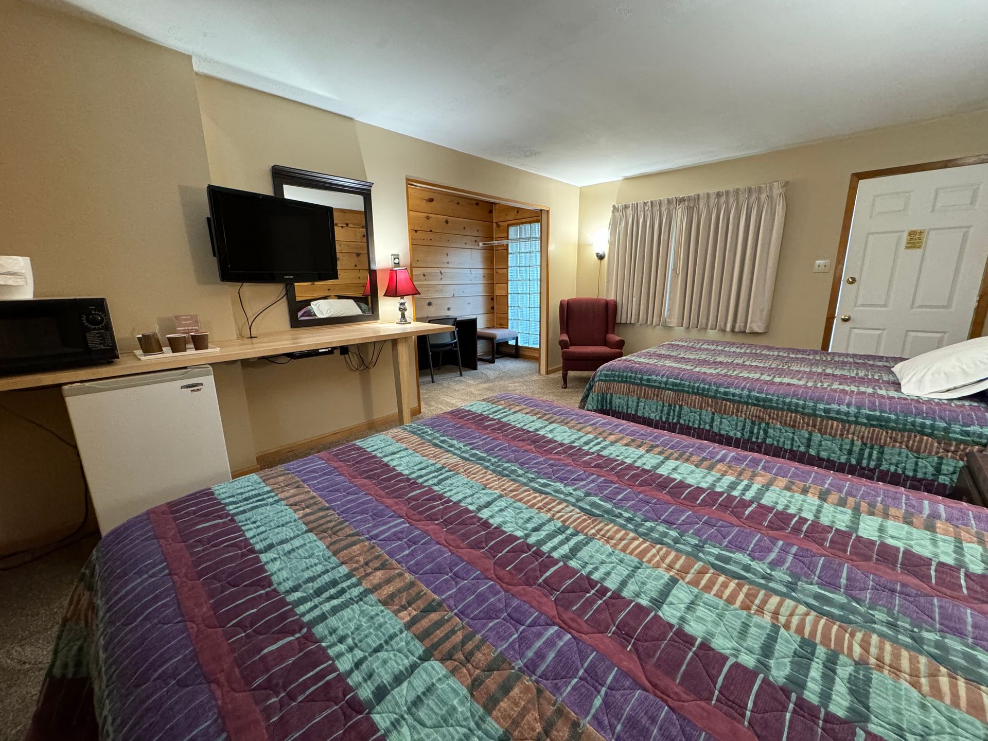 A hotel room with two beds , a television and a microwave.