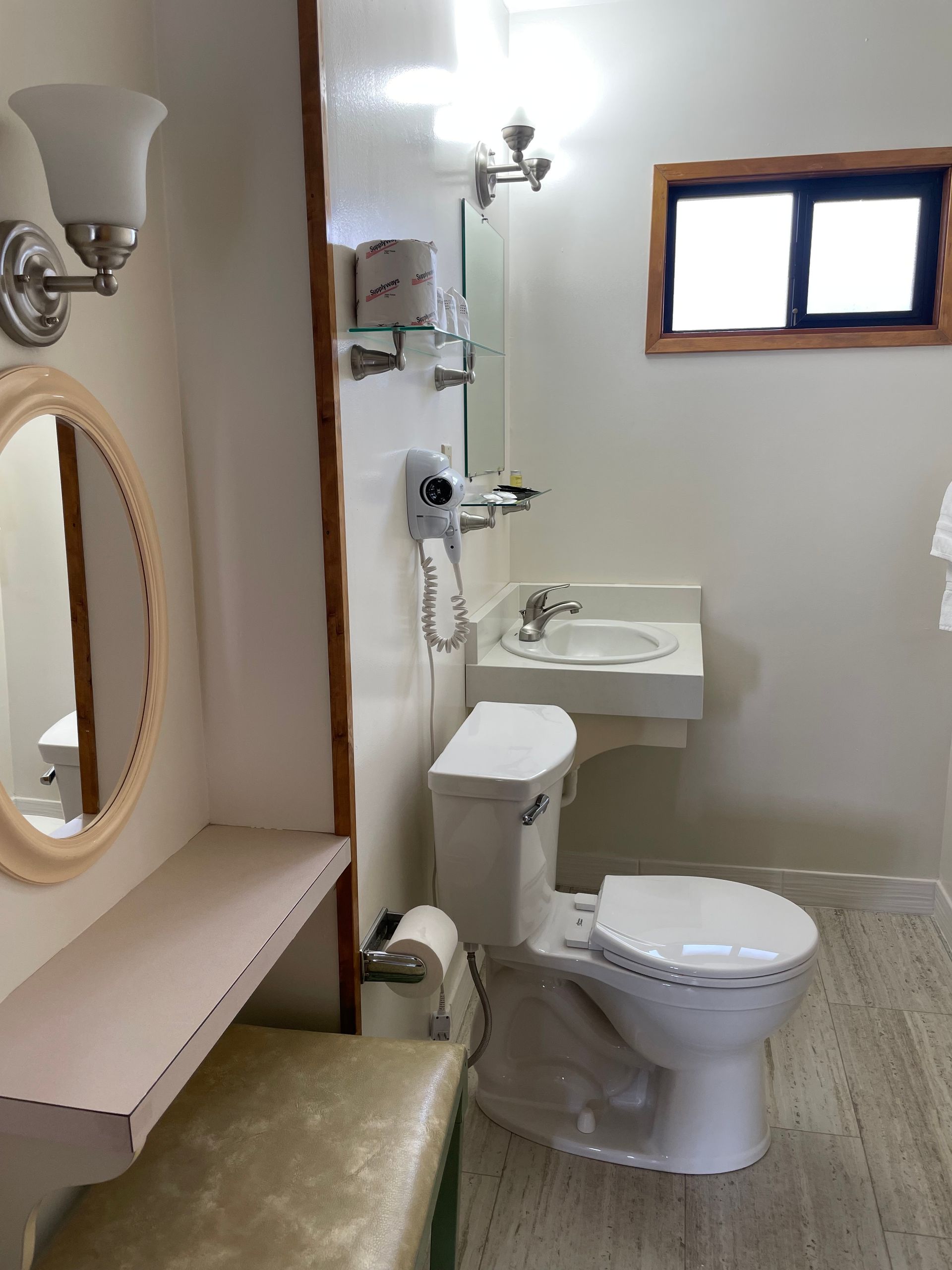 A bathroom with a toilet , sink and mirror.