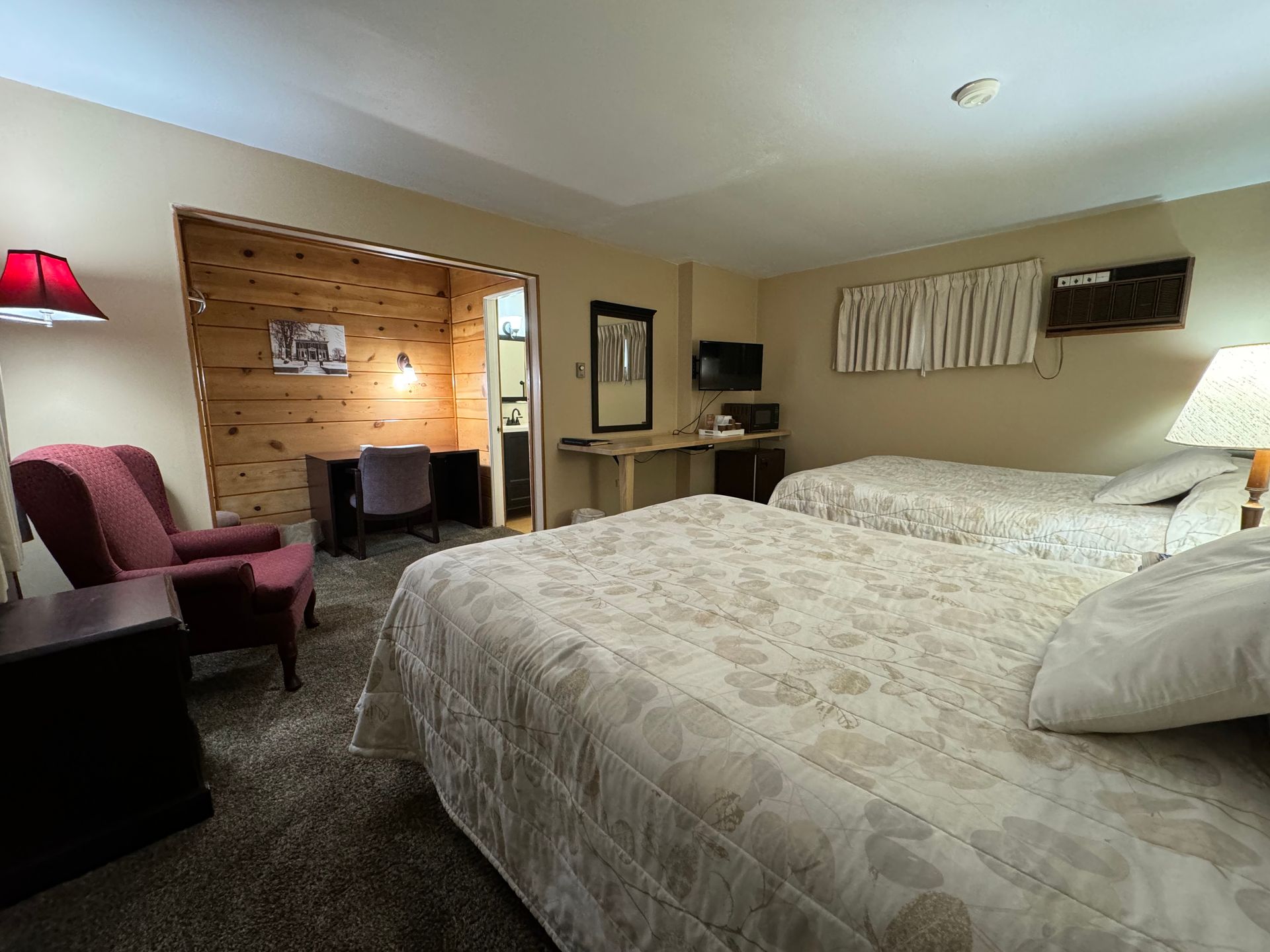 A hotel room with two beds , a chair and a desk.