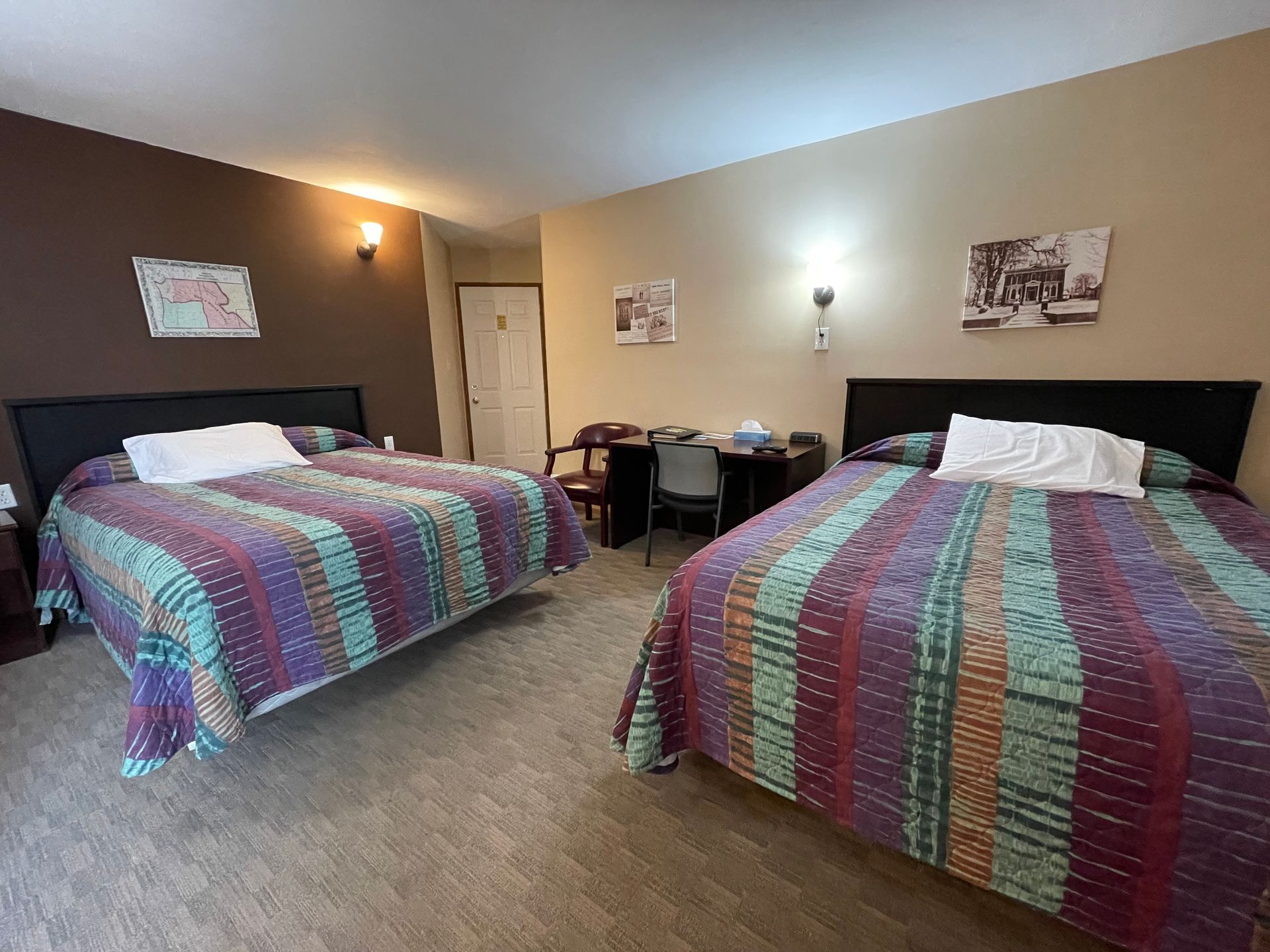 A hotel room with two beds and a desk.