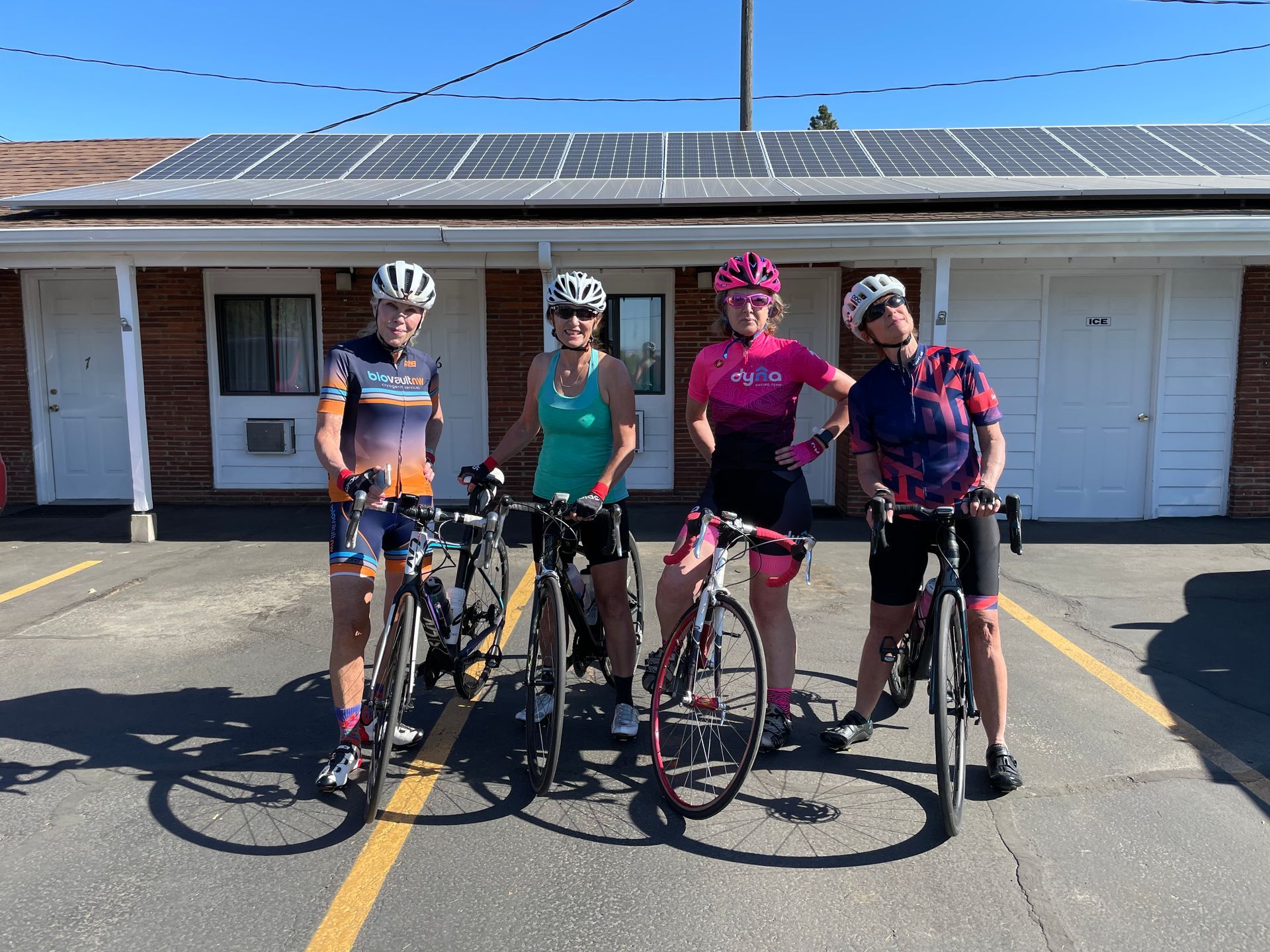 A group of women are standing next to their bicycles in a parking lot.