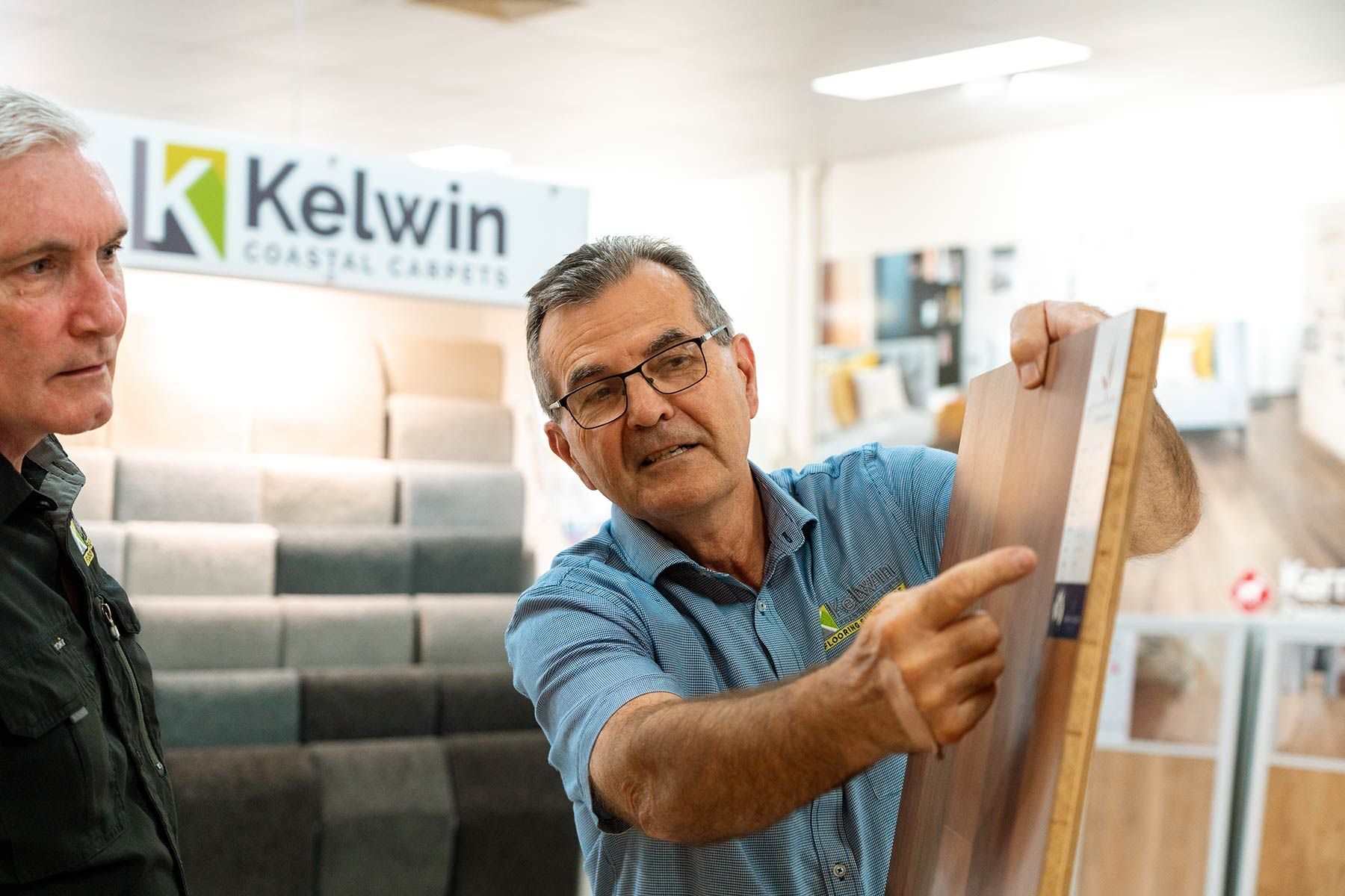 Two Men Are Looking at A Piece of Wood in A Store — Kelwin Coastal Carpets In Kundra Park, QLD