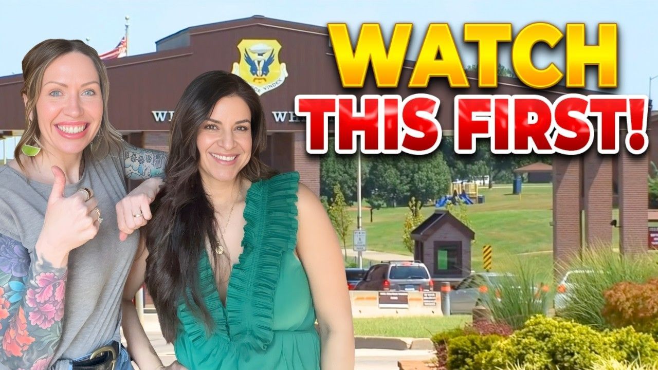 Two women smiling in front of a military base gate, with the bold yellow text 