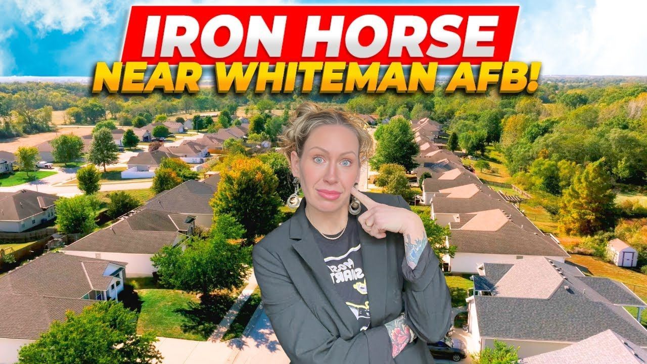 A person in a blazer points to their cheek in front of an aerial view of a suburban neighborhood titled Iron Horse.