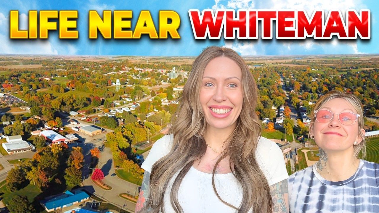 Two people smiling in front of a drone view of a small town under a blue sky, with text reading LIFE NEAR WHITEMAN.