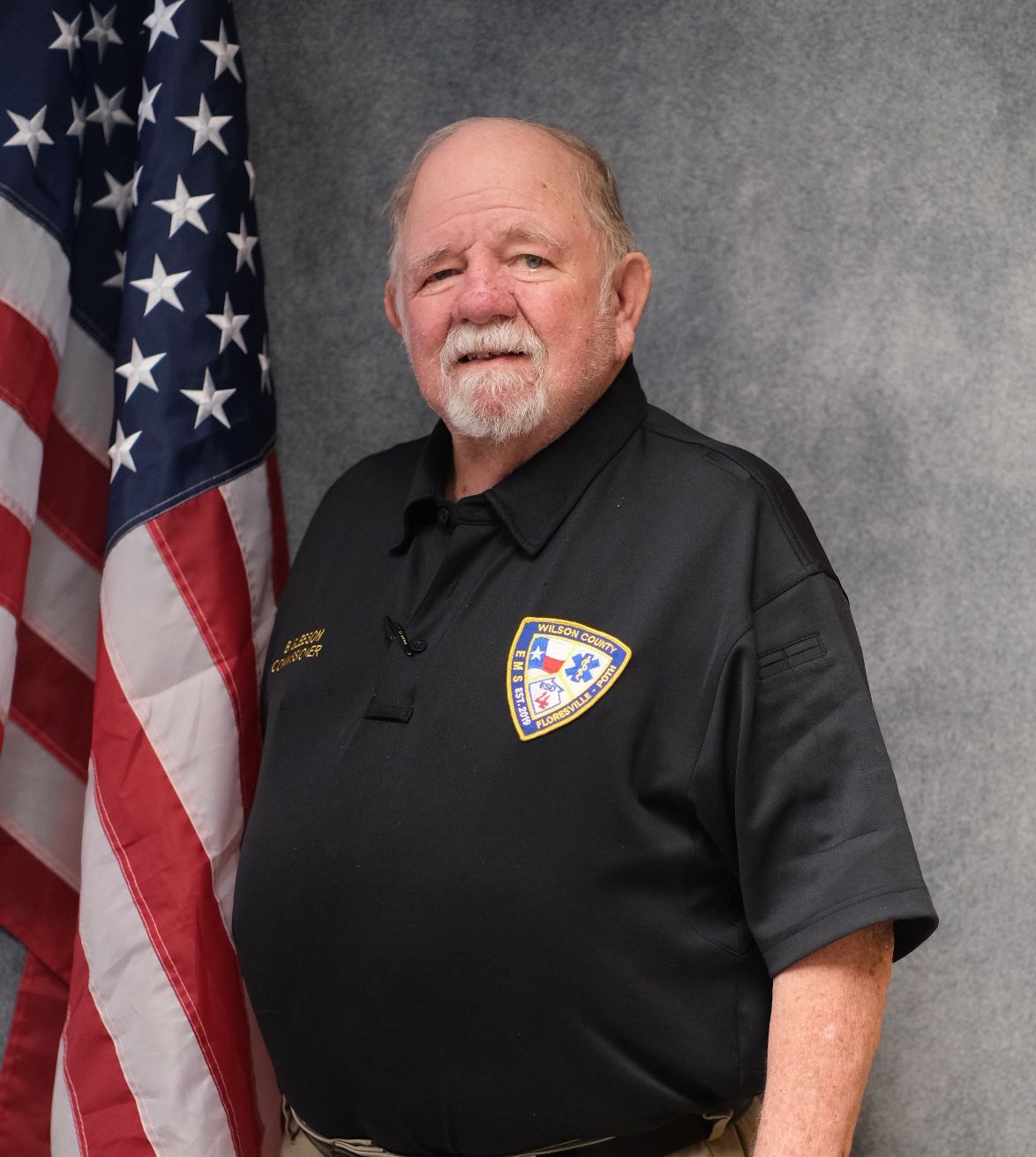 A man with a beard is wearing a black shirt and smiling.