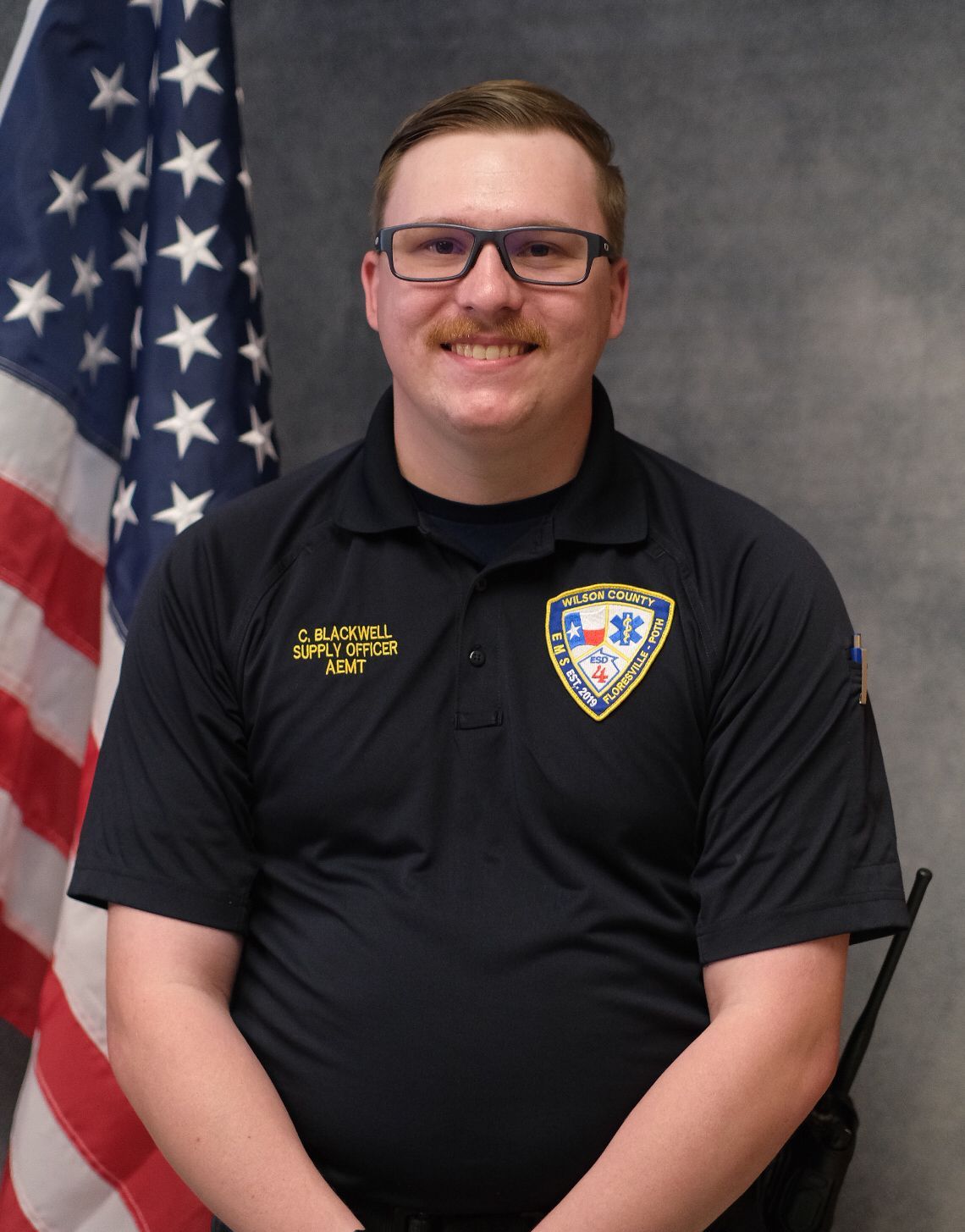 A man wearing glasses and a black shirt with the name c. blackwell on it