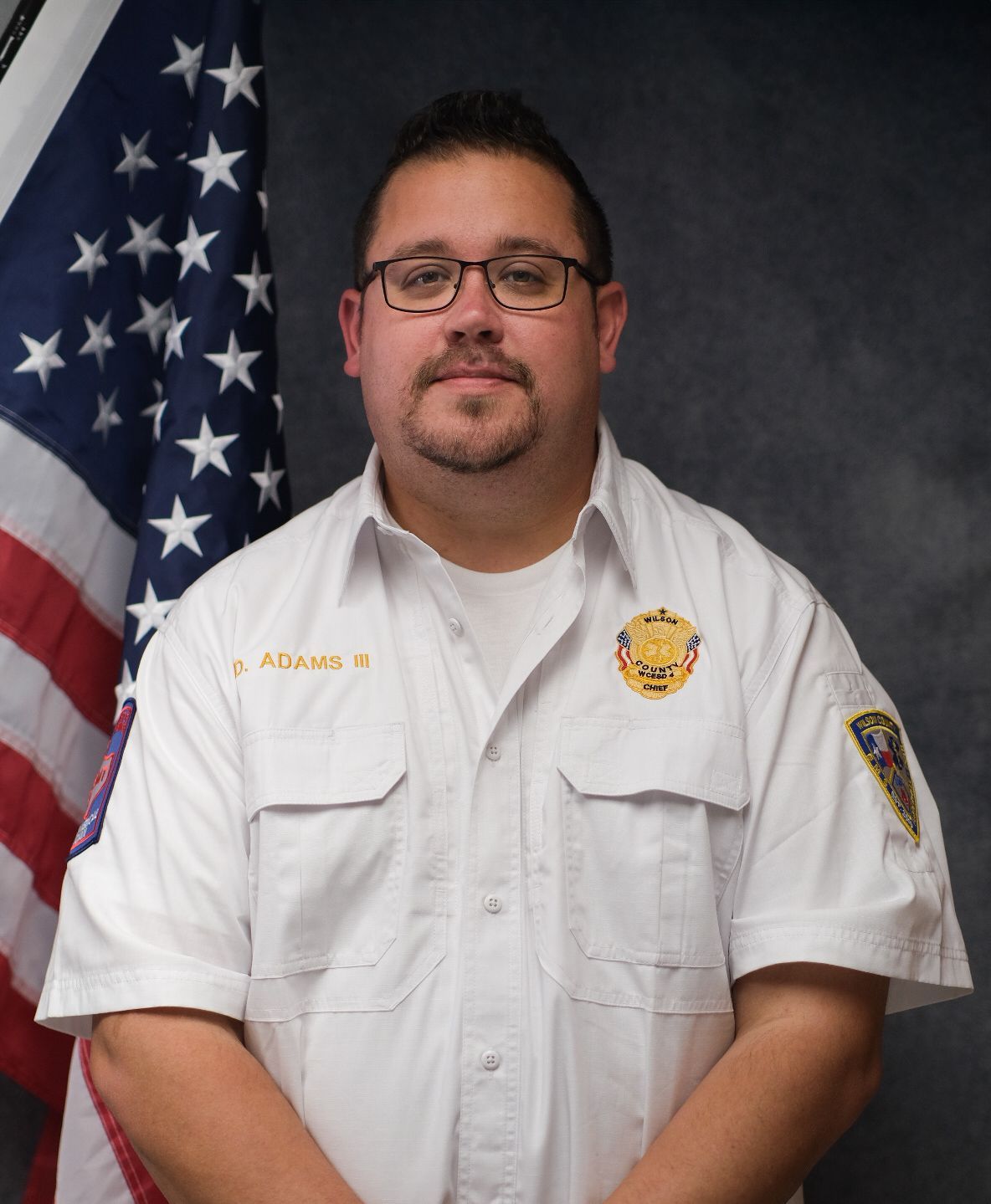 A man wearing glasses and a black shirt with the name adams on it