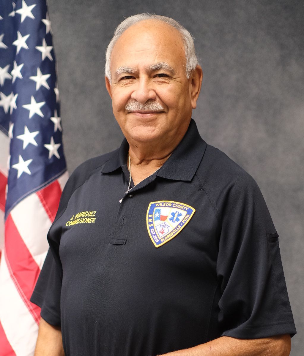 A man with a mustache is wearing a blue shirt and smiling.