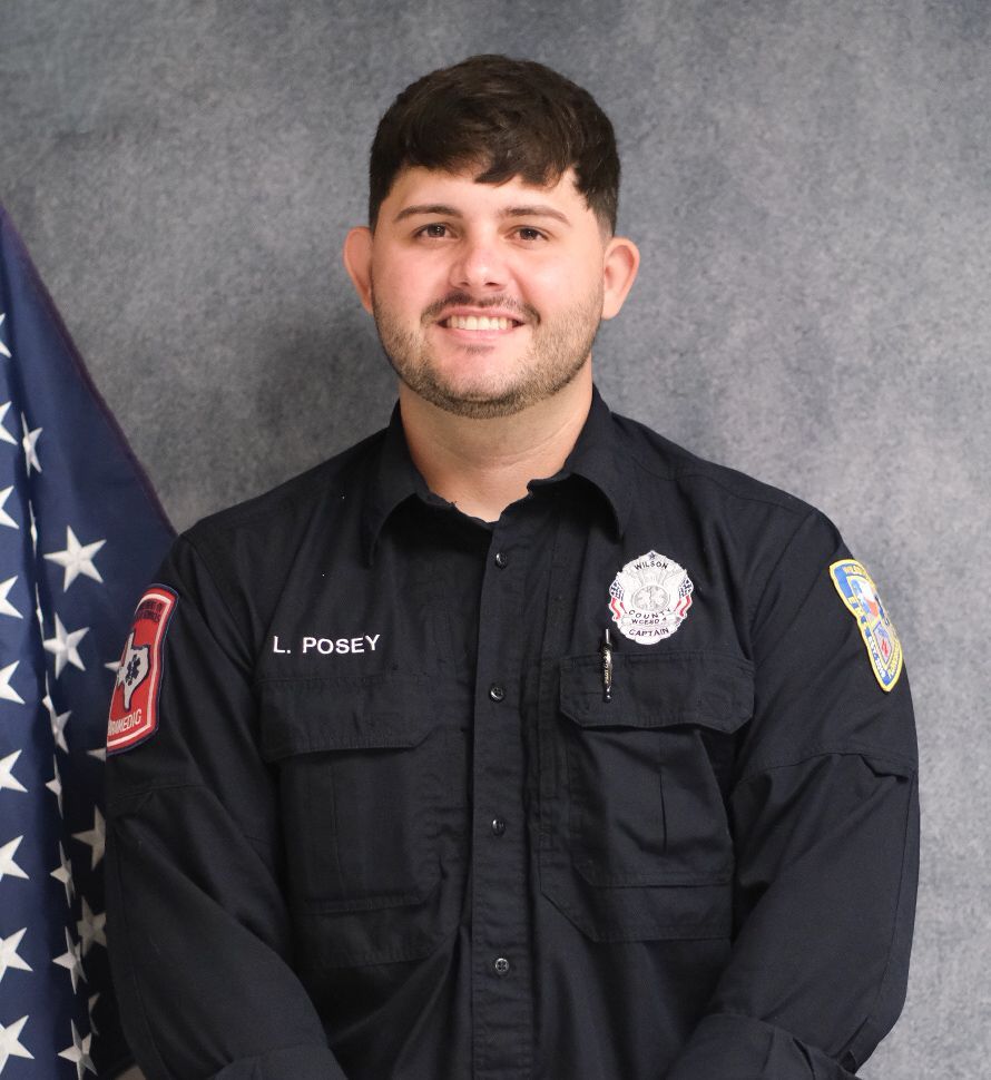 A man wearing a black shirt with the name captain paramedic on it is smiling for the camera.