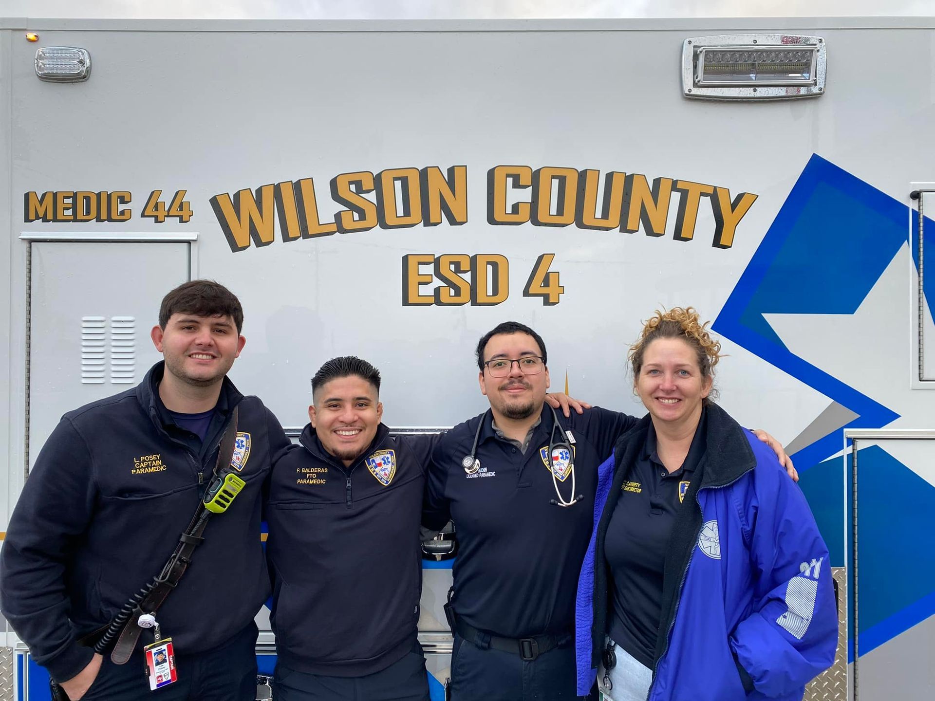 A group of paramedics are posing for a picture in front of a Wilson County ambulance.