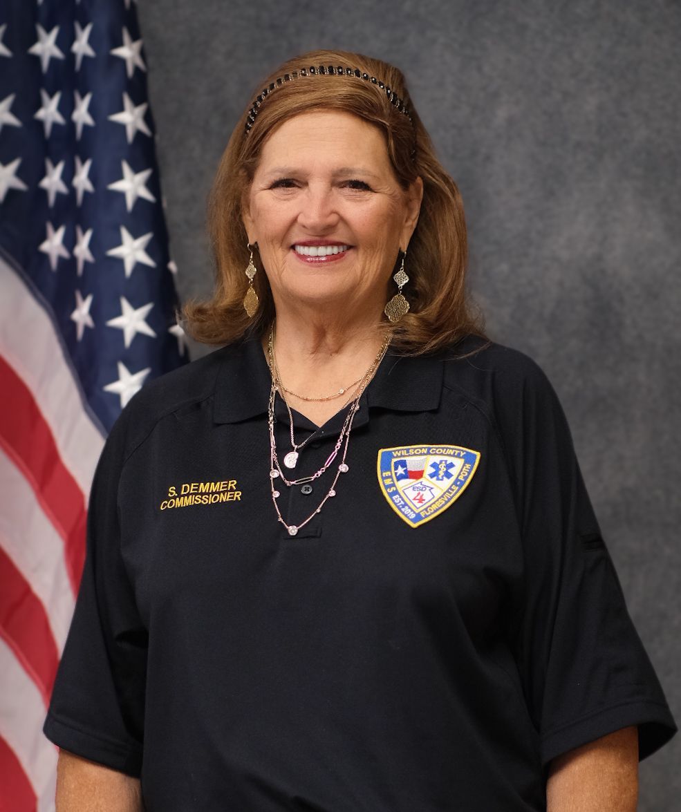 A woman wearing glasses and a blue shirt is smiling for the camera.