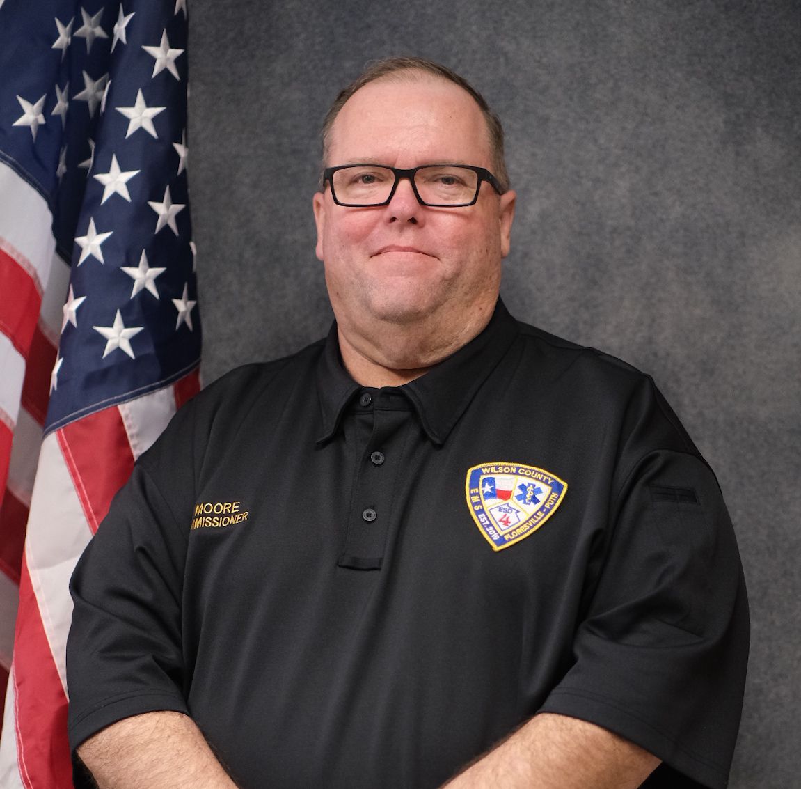 A man wearing glasses and a black shirt is smiling for the camera.