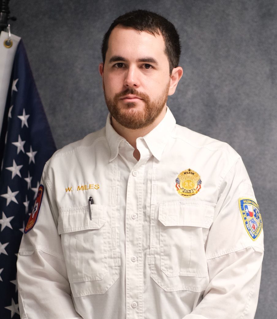 A man with a beard and a badge on his shirt is smiling for the camera.