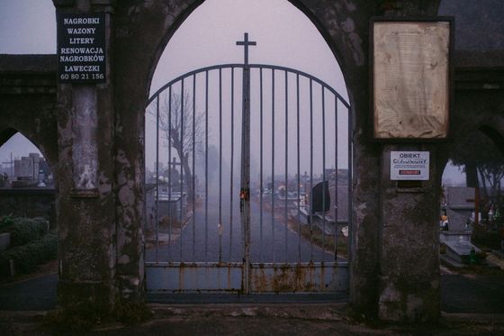 A cemetery gate with a cross on top of it