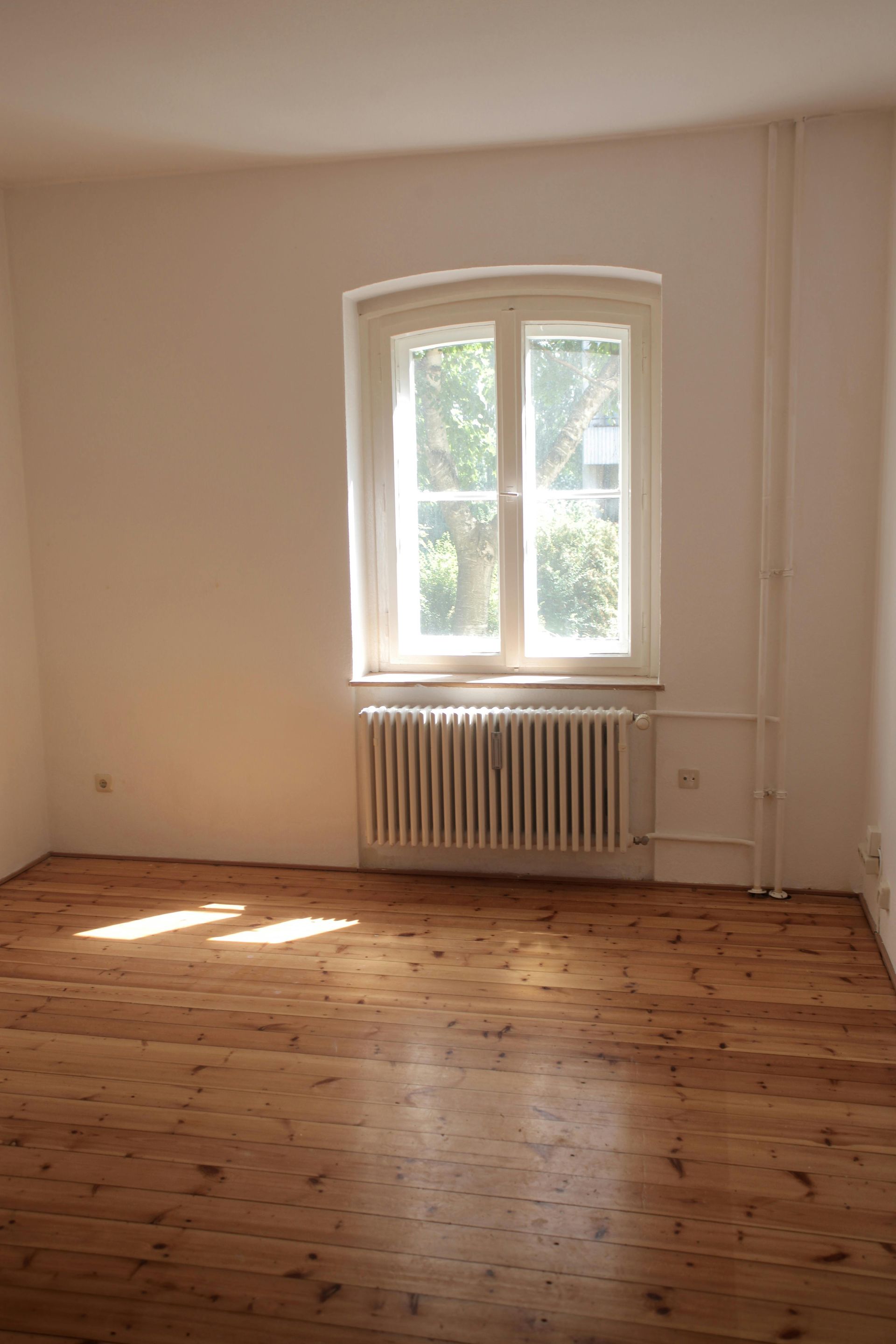 An empty room with a wooden floor and a window