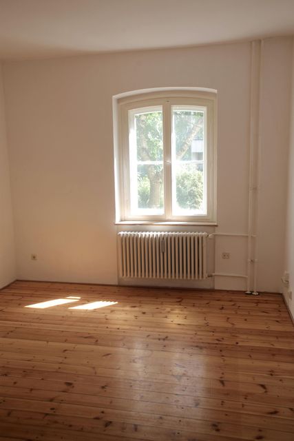 An empty room with a wooden floor and a window