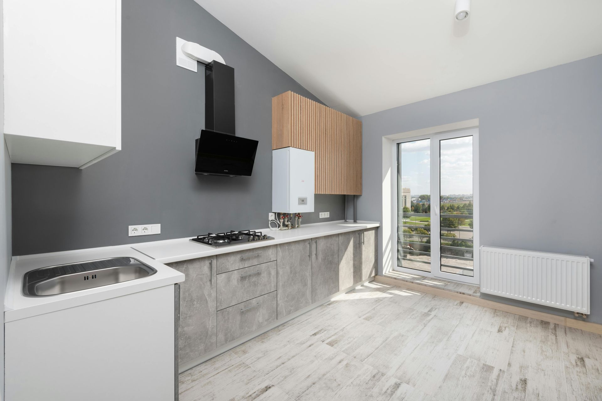 An empty kitchen with a sink , stove , and window.