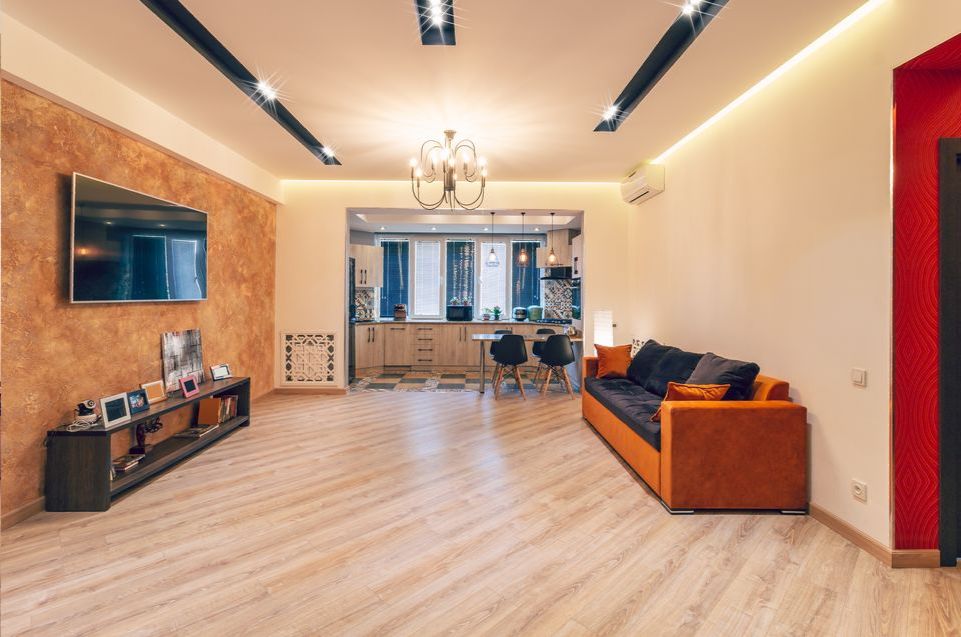 A living room with a couch and a flat screen tv on the wall.