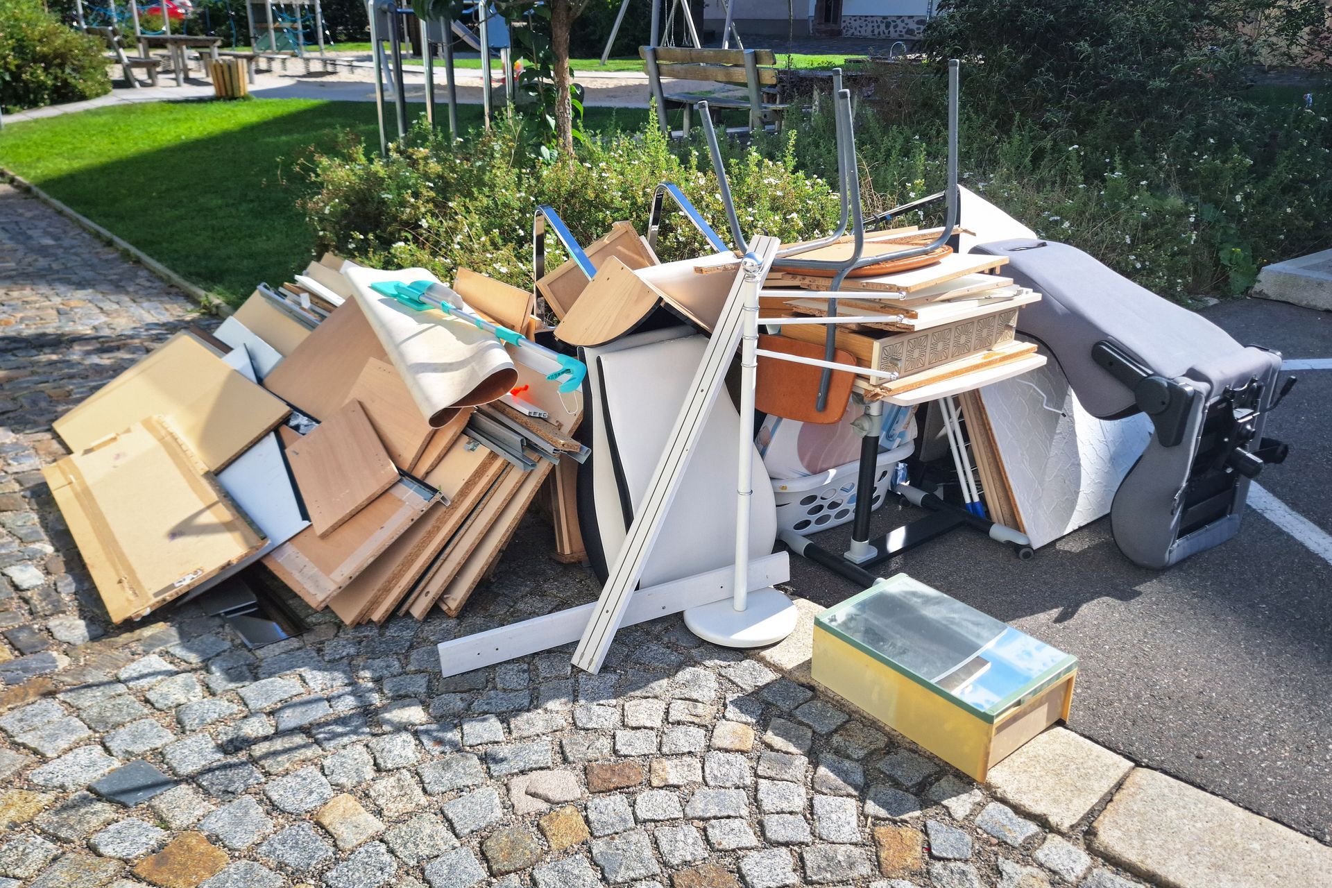 Movers in blue uniforms loading a white couch into a van, surrounded by boxes and furniture.