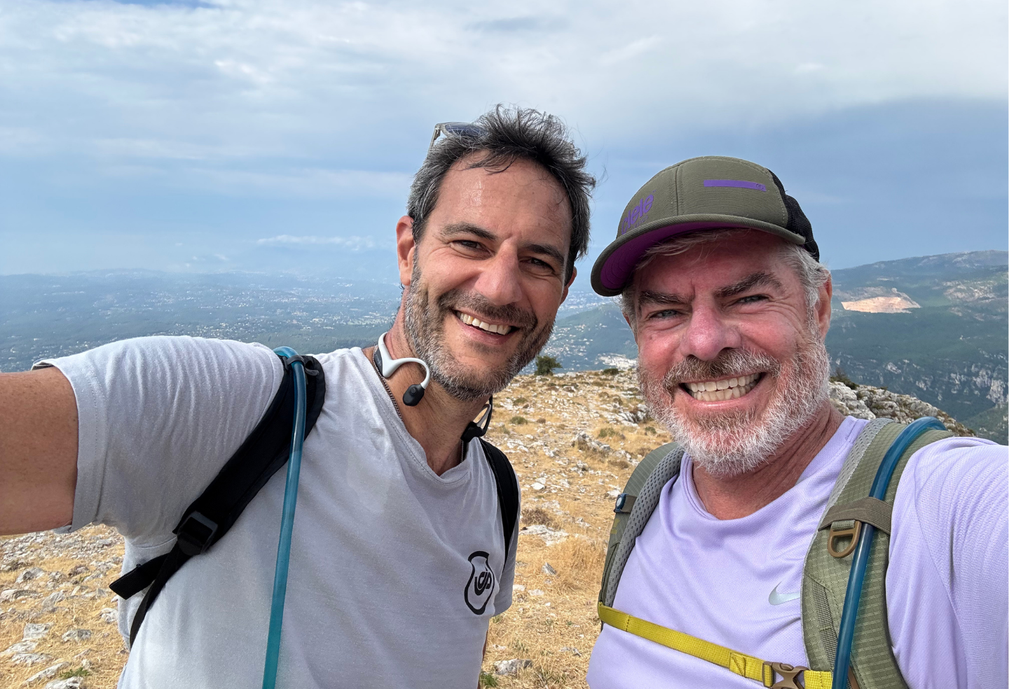 Two men are taking a selfie on top of a mountain.
