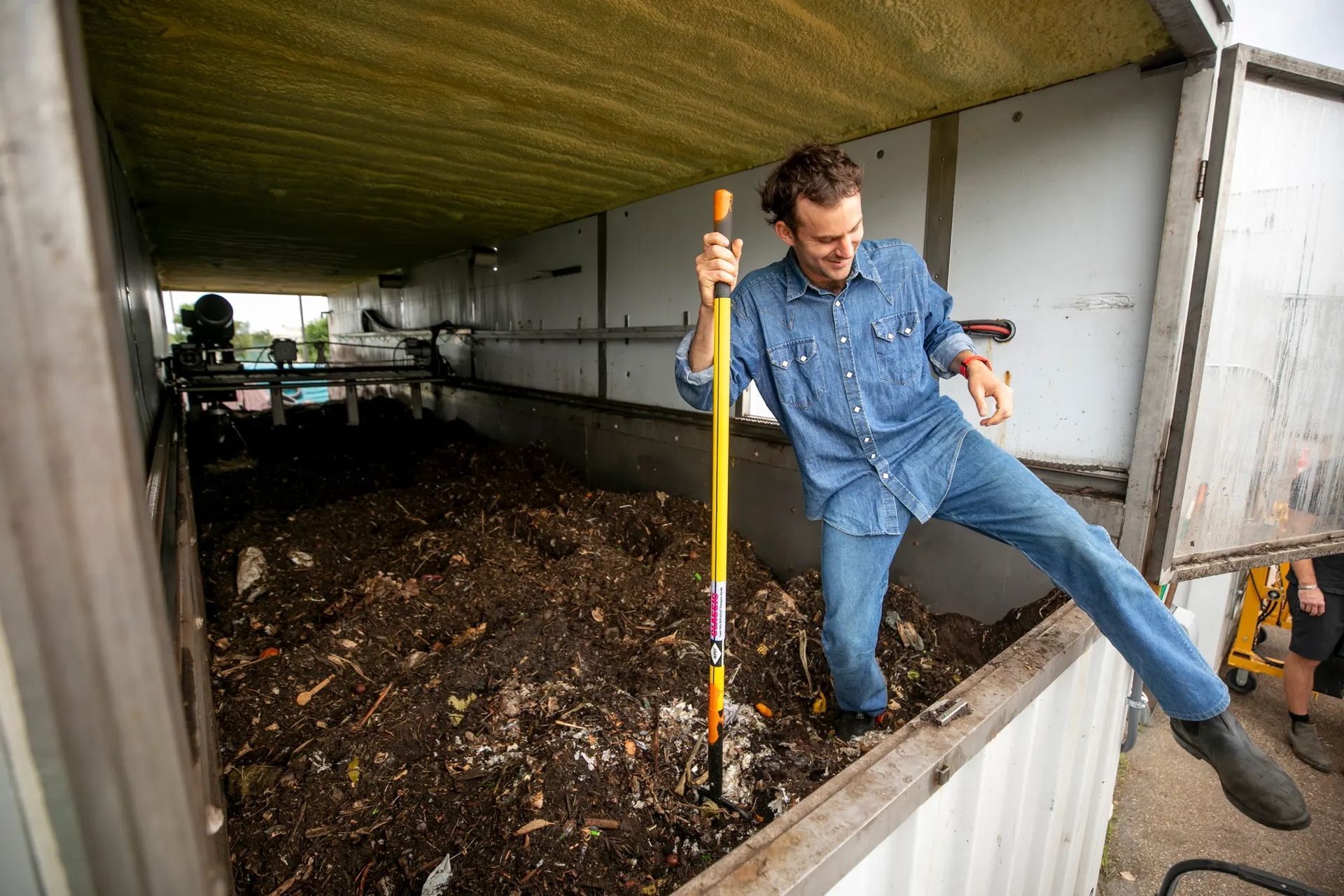 A small green seedling growing out of a pile of dark brown soil.