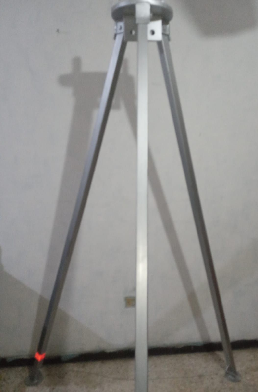 Un trípode está sentado frente a una pared blanca.