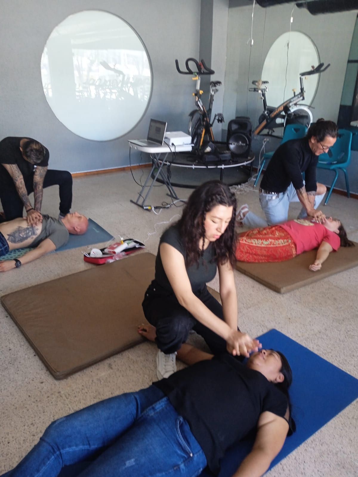 Un grupo de personas está practicando primeros auxilios en un gimnasio.