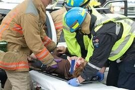 Un grupo de bomberos y paramédicos están ayudando a una persona en una camilla.