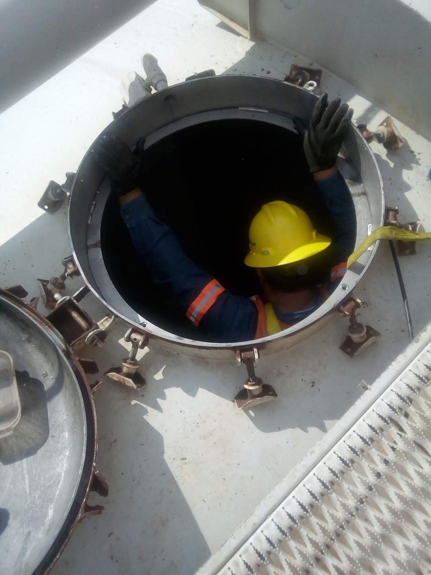 Un hombre con un casco amarillo sale arrastrándose de un agujero.